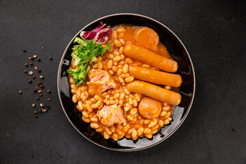 Beans with meat in tomato sauce cassoulet sausages, pork main course tasty snack fresh delicious gourmet food table setting rustic food top view copy space