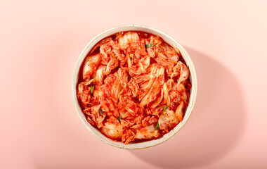Top view of traditional Korean kimchi in bowl on pink background. Healthy probiotic. Asian food