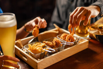 Beer snacks assortment with fries, onion rings and chicken bites
Crispy bar food served in a wooden tray with beer
Fried appetizer platter being shared at a pub