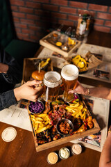 Beer snacks assortment with fries, onion rings and chicken bites
Crispy bar food served in a wooden tray with beer
Fried appetizer platter being shared at a pub