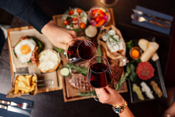 Clinking red wine glasses over a gourmet steak dinner
Elegant dinner scene with red wine and grilled steaks
Celebratory wine toast above a rich meat platter