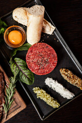 Beef tartare served with classic garnishes
Gourmet steak tartare with egg yolk and baguette
Raw beef tartare elegantly plated on a black dish