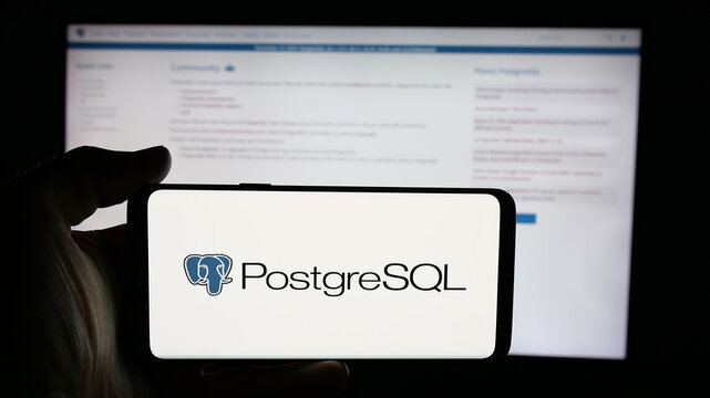 Stuttgart, Germany - 11-19-2025: Person holding cellphone with logo of database management system PostgreSQL on screen in front of webpage. Focus on phone display.