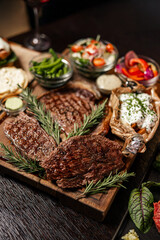 Grilled steak assortment served with fresh sides and herbs
Beef steaks on wooden boards with vegetables and sauces
Steak platter featuring ribeye and rustic garnishes