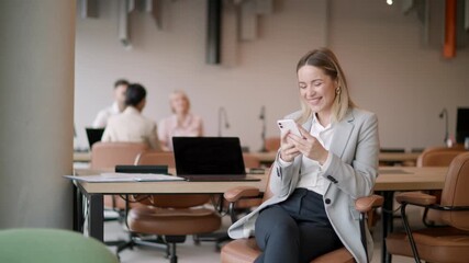 Bright office buzzing with activity as a businesswoman engages happily on her phone while colleagues work in the background.