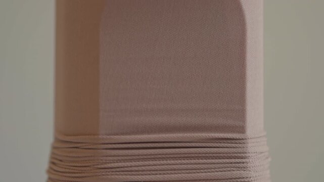 A close view of a compression stocking stretched on an assist device, highlighting the elastic fabric prepared for supportive medical use at home.