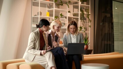 Bright and inviting lounge area fills with laughter as three friends collaborate over ideas and technology in a warm afternoon light. - Powered by Adobe