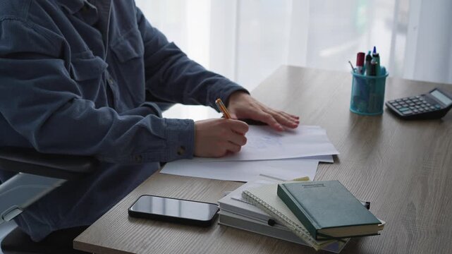 A man sits at a desk, writing something with a pen on a white sheet of paper.
A screenwriter writes a text on a piece of paper.
Education and training, a smart guy writes something with a pen.
Writing