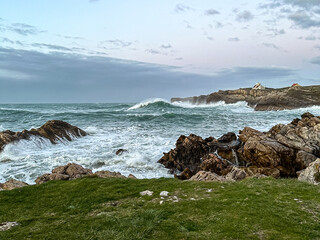 Wild ocean landscape with turbulent sea and rocky shore during twilight