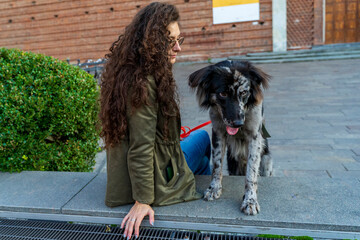 Woman with long curly hair and her spotted dog sitting outdoors connecting