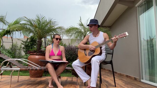 casal cantando e tocando viol&atilde;o ac&uacute;stico em casa 