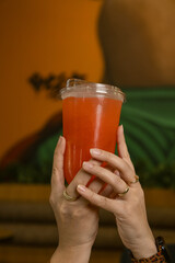 Hand Holding a Cold Red Refreshing Drink in Plastic Cup