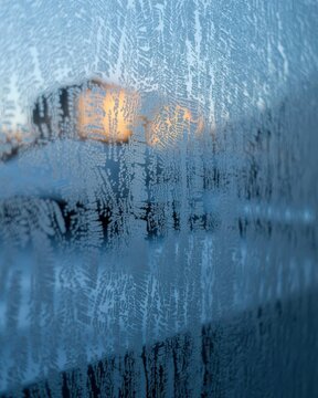 Blue frost macro on window with sunrise bokeh &mdash; cozy winter background for holiday cards