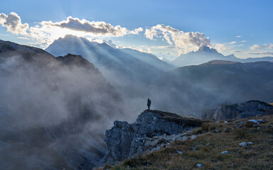 Female is shooting the sunset at view point on impressive jagged peaks of Cadini di Misurina mountain group in Tre Cime di Lavaredo park. Family vacation in Dolomites, Italy. Autumn, mist, clouds.