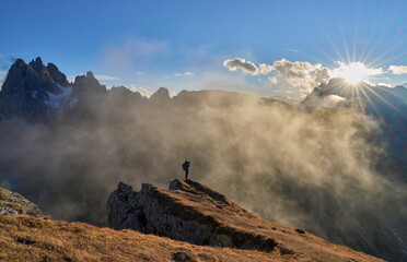 Female is shooting the sunset at view point on impressive jagged peaks of Cadini di Misurina mountain group in Tre Cime di Lavaredo park. Family vacation in Dolomites, Italy. Autumn, mist, clouds.