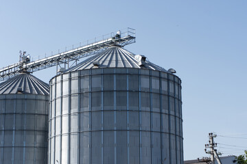 Silos stand tall against a clear sky in a rural farming landscape during midday hours