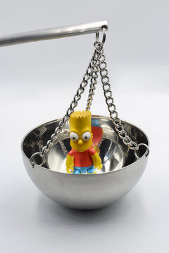 Bart Simpson toy in hanging metal bowl closeup.