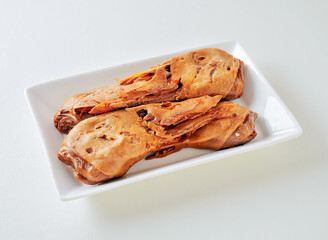 Braised duck heads, a traditional Asian delicacy, presented on a clean white plate. Savory and flavorful.