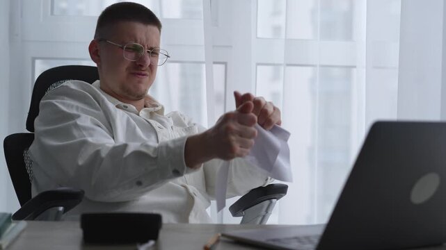 An angry businessman scatters torn and wrinkled paper around the office.
A man is having problems at work.
A man has a nervous breakdown at work and tears up paper.
Paper, stress, nerves, emotions