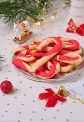 Christmas candy cane shortbread cookies on a plate with Christmas decor on a light tablecloth. Merry Christmas.