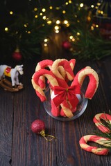 Christmas candy cane shortbread cookies in a clear glass vase with Christmas decor on a dark wooden background. Merry Christmas.