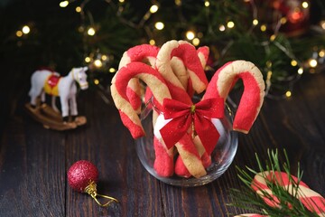 Christmas candy cane shortbread cookies in a clear glass vase with Christmas decor on a dark wooden background. Merry Christmas.