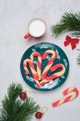 Christmas candy cane shortbread cookies on a green plate with Christmas decor against a white concrete background. Merry Christmas.