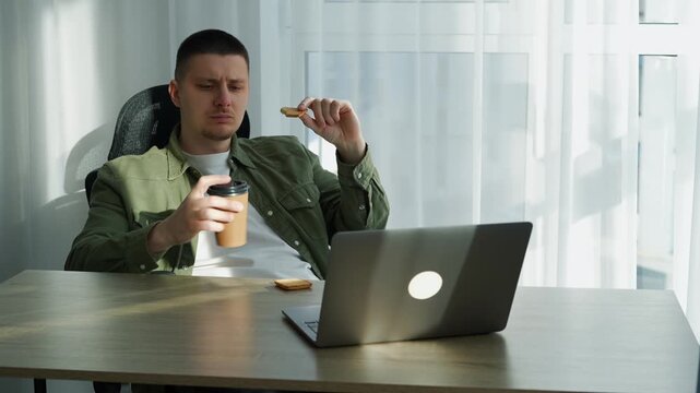 A man eats a sandwich at work. Lunch break in the office.
A man satisfies his hunger with a delicious meal and eats oatmeal chili cookies at his desk.
Workplace, desk, man, hungry, appetite, calories