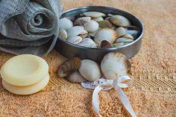 Still life composition with bath sponge, natural soap bars, and seashells on a peach towel, creating a soothing atmosphere for relaxation and personal self care rituals