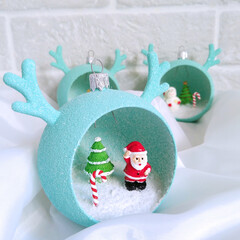Christmas decorations in the shape of a ball with horns and small figures inside. Decorative gift balls for decorating your home, office, or as gifts. A Christmas tree, Santa Claus, snowman, and bunny