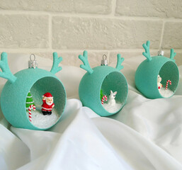 Christmas decorations in the shape of a ball with horns and small figures inside. Decorative gift balls for decorating your home, office, or as gifts. A Christmas tree, Santa Claus, snowman, and bunny