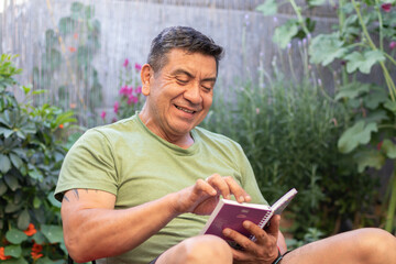 Hombre de 60 años con ropa deportiva leyendo una libreta de apuntes rodeado de un jardín verde