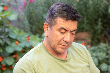 Hombre de 60 a&ntilde;os con ropa deportiva leyendo una libreta de apuntes rodeado de un jard&iacute;n verde