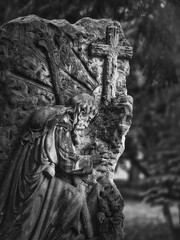Stone relief of Jesus praying before the cross at Goat Gate Cemetery in Bratislava, photographed in black and white.