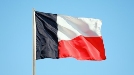 A black white and red tricolor flag waves on a wooden pole against a clear blue sky