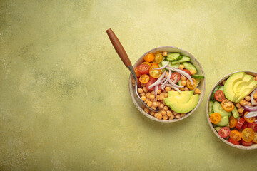 Two bowls with vibrant vegetarian chickpea salad with fresh vegetables in ceramic bowls top view on