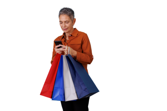 Senior woman shopping, carrying colorful paper bags and browsing social media or apps on her smartphone. Transparent background