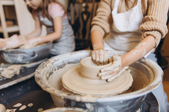 Children learning pottery craft on a spinning wheel