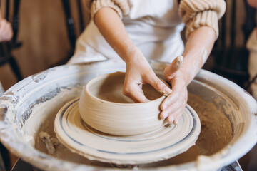 Child hands shaping clay on pottery wheel