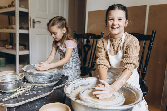 Children creating pottery on wheels in workshop - Powered by Adobe