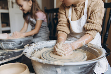 Children learning pottery craft on a spinning wheel
