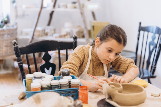 Young girl learning pottery craft in workshop
