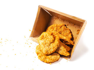 Uncooked chicken goujons or tenders in a card board box on white background. Popular classic chicken dish made from pieces of breast and breadcrumbs. Traditional ready to cook poultry product.