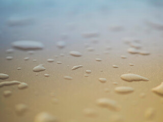 Water droplets on a metal surface. The droplets are of different sizes and are scattered all over the image. The image has a dreamy, ethereal quality to it. Design background.