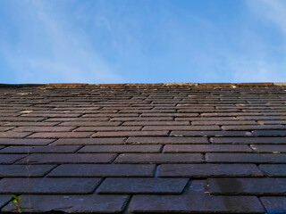 A slate tiled old roof with a blue sky in the background. Vintage technology.