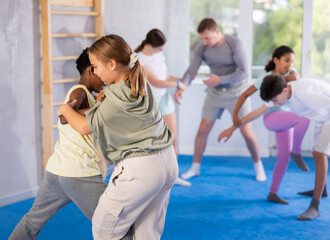 Boy and girl practicing self-defense techniques in group at gym..