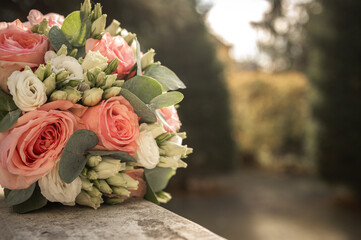 Beautiful bridal bouquet with pink roses, white eustoma and eucalyptus on a stone railing. Wedding floral decoration close-up with copy space on blurred background