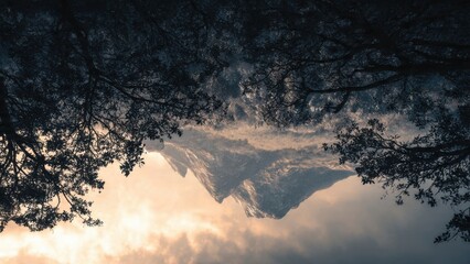 Stunning Mountain Peak Framed by Forest Trees under a Dramatic Sky at Sunrise Captured Upside Down Perspective