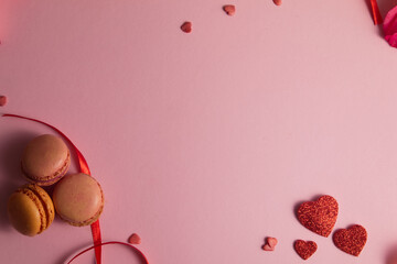 Valentine's Day Concept: Pink Background with Macarons, Glitter Hearts and Red Ribbons (Flat Lay)