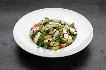 Fresh avocado and feta salad with arugula, cherry tomatoes and balsamic drizzle